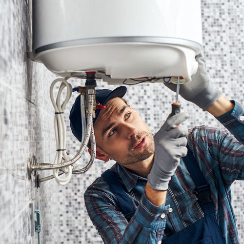 Almost done. Worker set up electric heating boiler at home. Close-up of young handyman