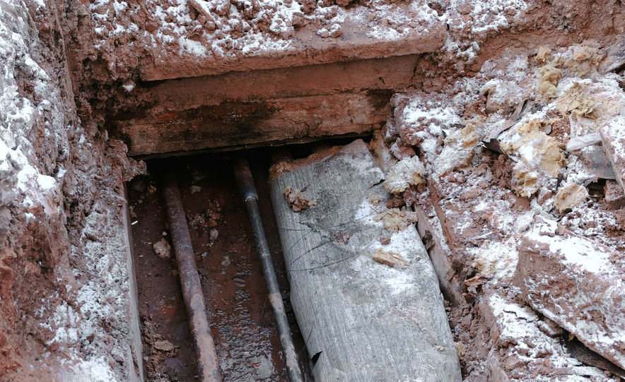 Crash, burst pipes and leaking water under the earth. Excavated pipes in the winter